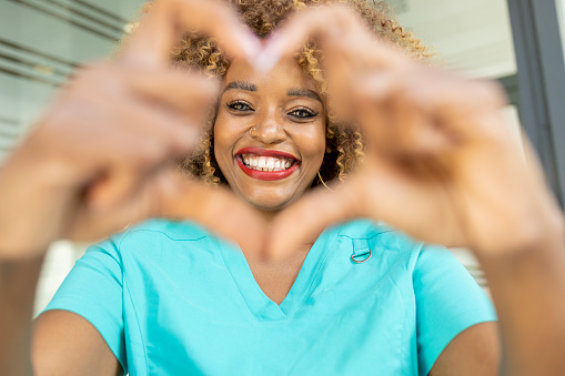 Happy nurse laughing and making heart shape with her hands
