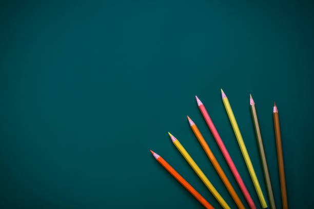 Back to school concept with colored pencils  arranged in a semicircle on dark green background. Close up. Art and craft. Design professional.  Education. Office supplies. Flat lay. Copy space. Top view. Pastel colors.