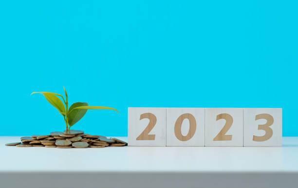 istock Heap of coins and number 2023 on white table 1441650434