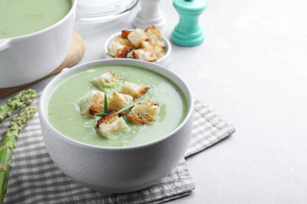 istock Bowl of delicious asparagus soup served on light grey table, space for text 1441651365