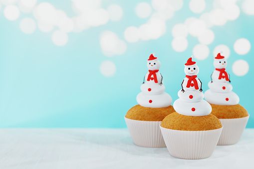 Christmas snowman cupcakes against Christmas lights. 3D render