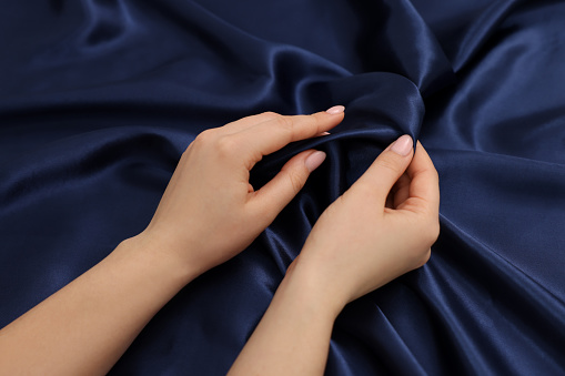 Woman touching smooth silky fabric, top view