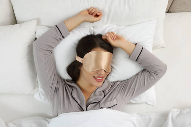 istock Young woman with sleeping mask in bed, top view 1441657159