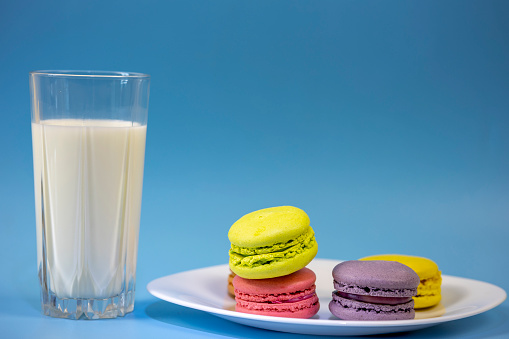 Assortment of delicate colorful macaroons and a glass of milk