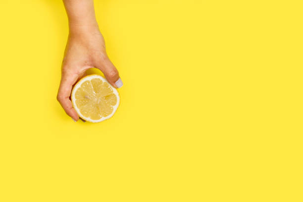 istock Woman holding a half orange on a a yellow background 1441661366