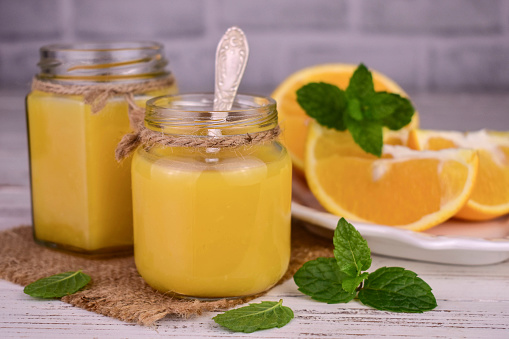 Orange cream (English citrus cream) in jars on a white wooden background.