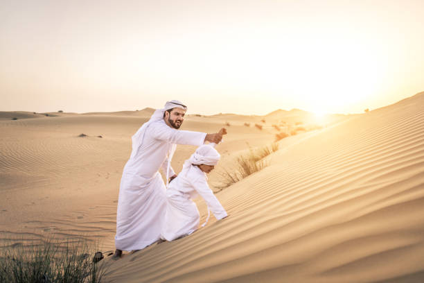 istock Arabian man and son playing in the desert 1441661526