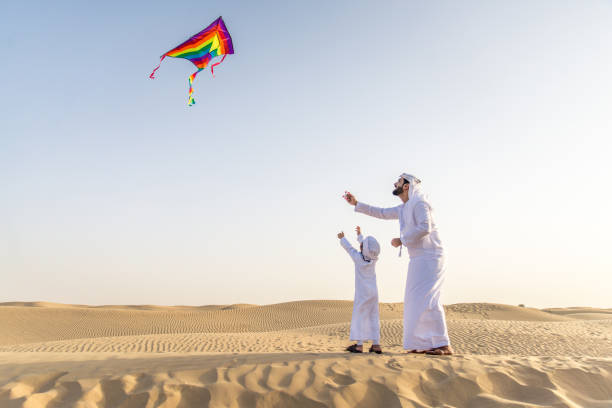Arabian man and son playing in the desert stock photo