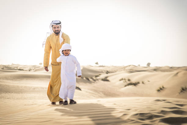istock Arabian man and son playing in the desert 1441662135