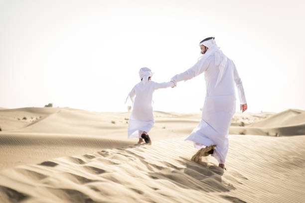 istock Arabian man and son playing in the desert 1441662328