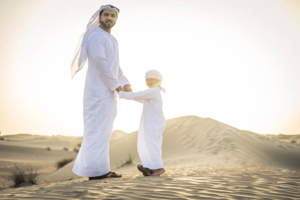 istock Arabian man and son playing in the desert 1441662450