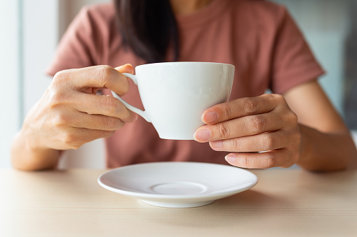 Cropped image of an Asian woman drinking coffee in cafe