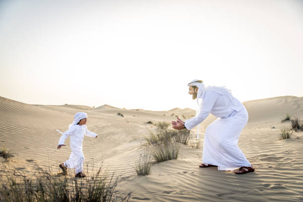 istock Arabian man and son playing in the desert 1441663282