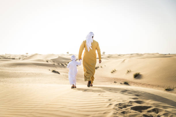 istock Arabian man and son playing in the desert 1441663441