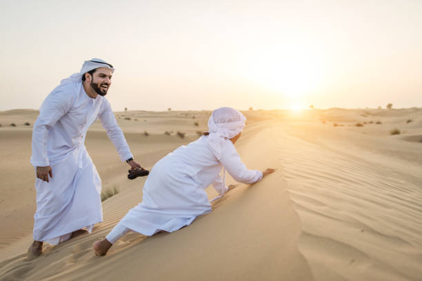 istock Arabian man and son playing in the desert 1441664468