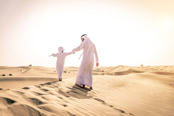 istock Arabian man and son playing in the desert 1441664508