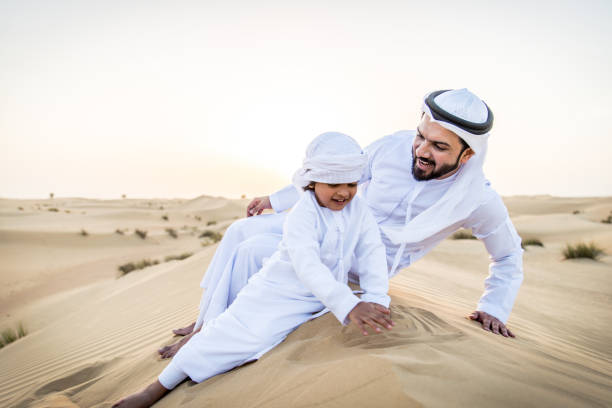 istock Arabian man and son playing in the desert 1441668297