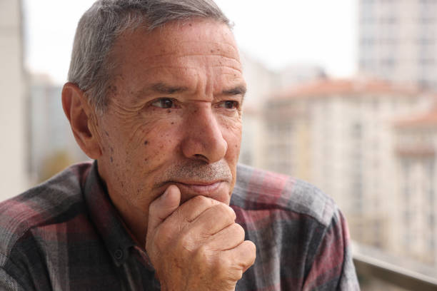 An old man is looking outside on balcony