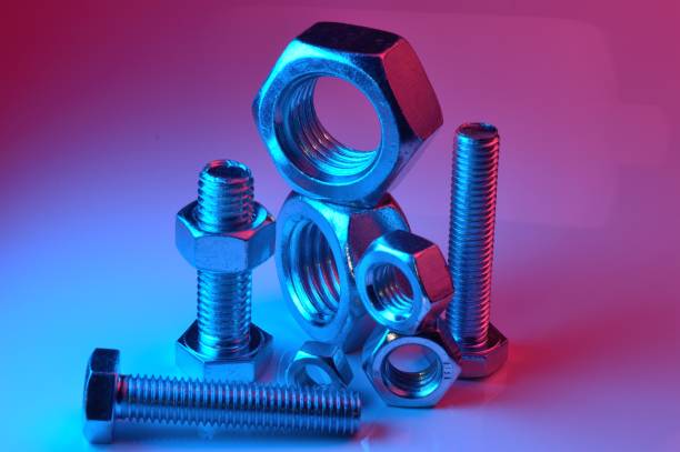 istock large and small nuts and bolts, highlighted in different colors, on a light background. 1441668448