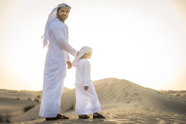 istock Arabian man and son playing in the desert 1441669082
