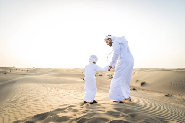 istock Arabian man and son playing in the desert 1441669244