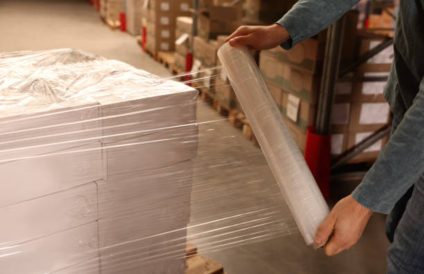 istock Worker wrapping boxes in stretch film at warehouse, closeup 1441669391