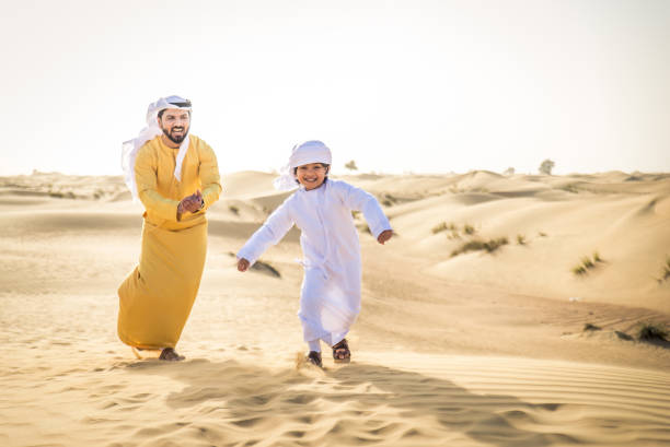 istock Arabian man and son playing in the desert 1441669409