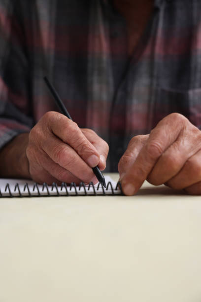 istock An old man is writing with his right hand a diary 1441670994
