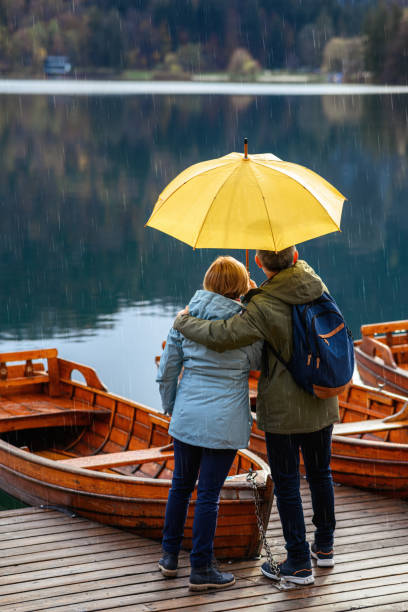 couple d’âge mûr profitant d’un jour de pluie - umbrella senior adult couple autumn photos et images de collection