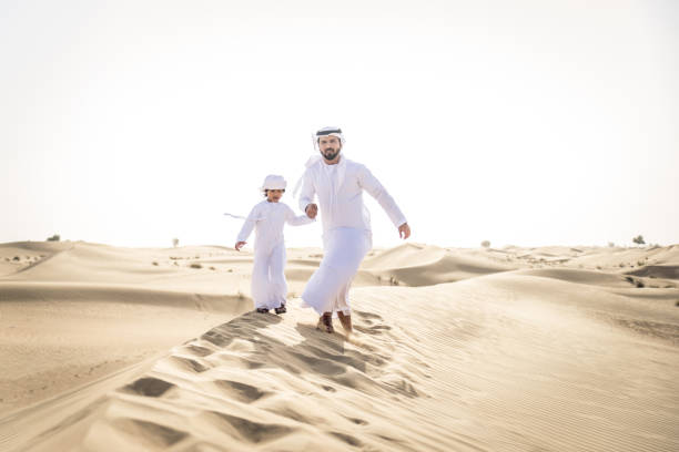 istock Arabian man and son playing in the desert 1441674734