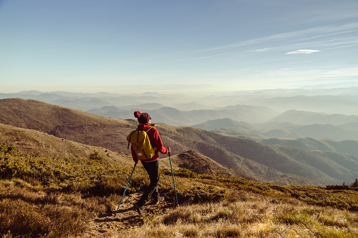 Rear view of a female hiker with back pack and hiking poles on a mountain peak