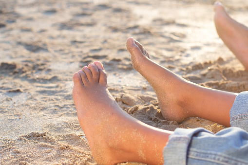 Close-up of African American family feet on beach. Adult and woman feet covered in sand. Family, relaxation, nature concept