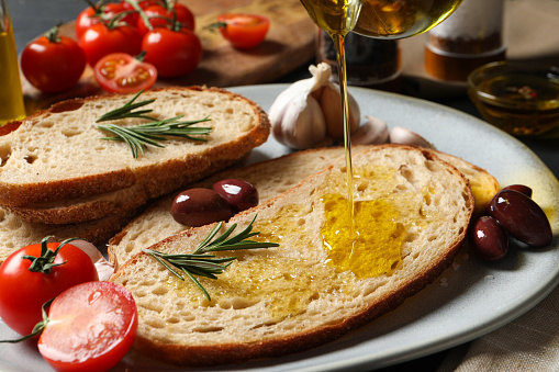 Pouring oil onto slice of bread on plate, closeup
