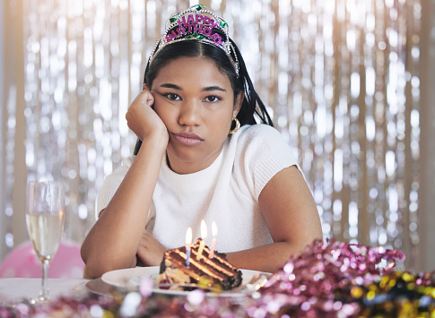 Bored, angry and birthday girl at a party at a celebration event with cake and candles upset. Portrait of a person from Mexico with sweet food feeling frustrated, sad and unhappy celebrating