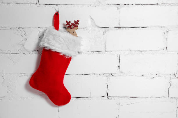 christmas sock with deer decoration hanging on white brick wall background. copy space stock photo