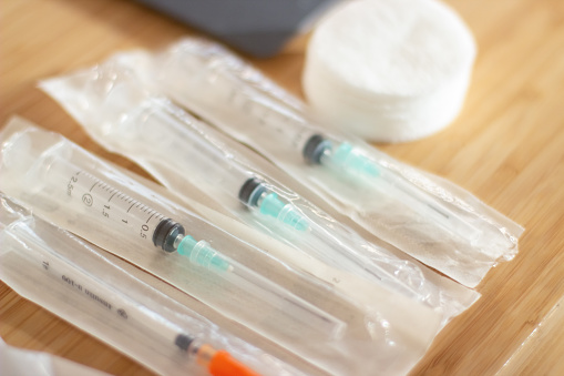 Close-up of syringes for coronavirus vaccination. Syringes and needles in packages on table prepared for injection during Covid-19 outbreak. Medical care and support for people during epidemic concept