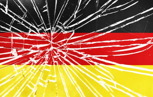 The cracks are showing: national flag of Germany behind broken glass, with heavy grain and other distressed elements.