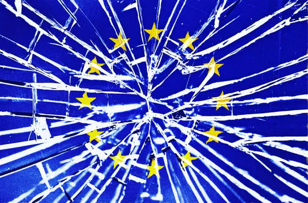 The cracks are showing: flag of the EU behind broken glass, with heavy grain and other distressed elements.