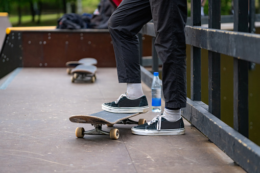 Close up of a skater standing on the ramp at extreme sport competition. Skate shoe on a skateboard