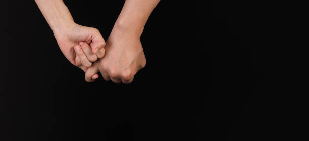 istock Hands is do a pinky promise gesture on black background 1441688847