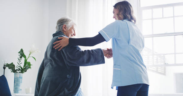 Nurse help old woman, bedroom nursing home and support, kindness and medical trust of homecare service. Caregiver, healthcare worker and elderly senior patient rehabilitation in happy retirement home stock photo