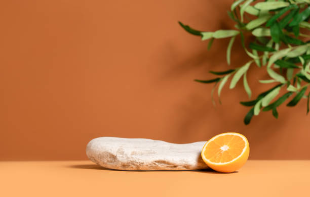 istock Beautiful template composition of empty mockup stage for product presentation made with stone, orange fruit and olive tree leaves. 1441690773
