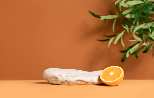 Beautiful template composition of empty mockup stage for product presentation made with stone, orange fruit and olive tree leaves.