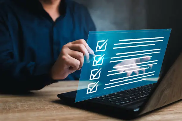 Photo of Business concept and smart checklist on virtual screen,A man use a pen marking about exploring the topics on the digital form check sheet and use a laptop working in a modern office