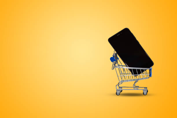 istock shopping cart and a phone on yellow background - space for text 1441693374
