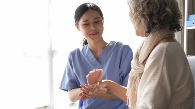 Asian young nurse supporting elderly patient disabled woman in hospital. Elderly patient care concept.