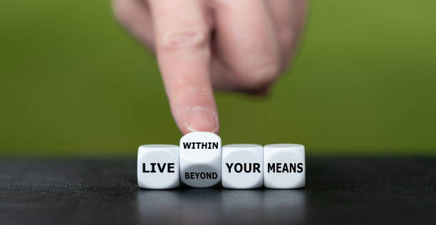 istock Hand turns dice and changes the expression 'live beyond your means' to 'live within your means'. 1441697773