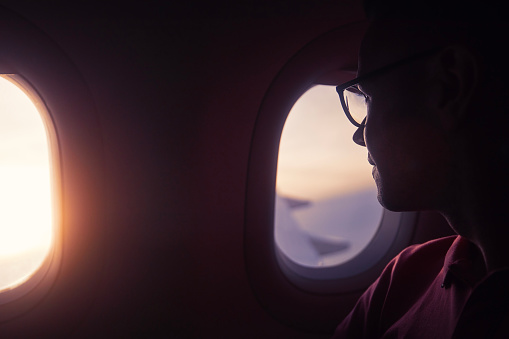 Passenger looking out through window of plane during beautiful sunset.