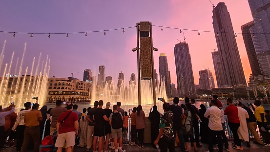 Dubai, United Arab Emirates – August 12, 2022: Tourists admiring the Burj Khalifa Water Fountains on an evening in Dubai, UAE.