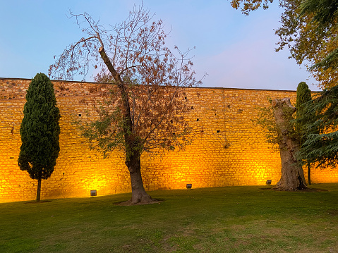 Walled garden yards, illuminated brick wall in the garden at dusk